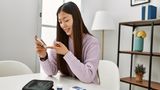 Ein junge Frau mit asiatischem Hintergrund misst ihren Glukosewert im Blut