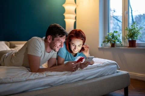 Symbolbild Google-Jahresrückblick: Zwei Menschen liegen mit Smartphones auf dem Bett