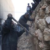 Männer machen sich mit Spitzhacke und Brechstange an einer Mauer im Gefängnis zu schaffen