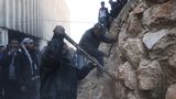 Männer machen sich mit Spitzhacke und Brechstange an einer Mauer im Gefängnis zu schaffen