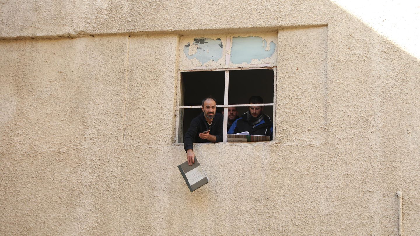 Ein Mann winkt mit Dokumenten aus einem Fenster des Gefängnisses