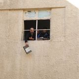 Ein Mann winkt mit Dokumenten aus einem Fenster des Gefängnisses