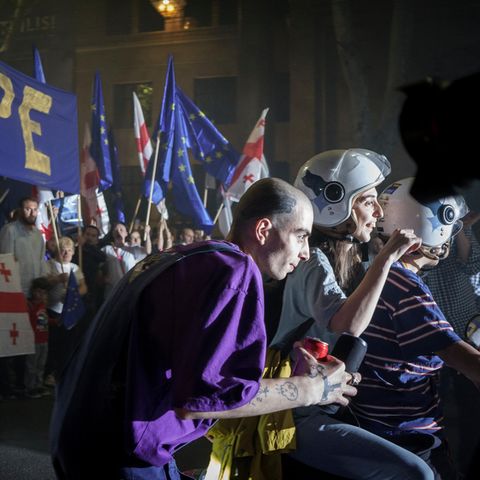 Georgia: A man plays music with his box during the protests. In the background the protest and a "Europe"-Banner