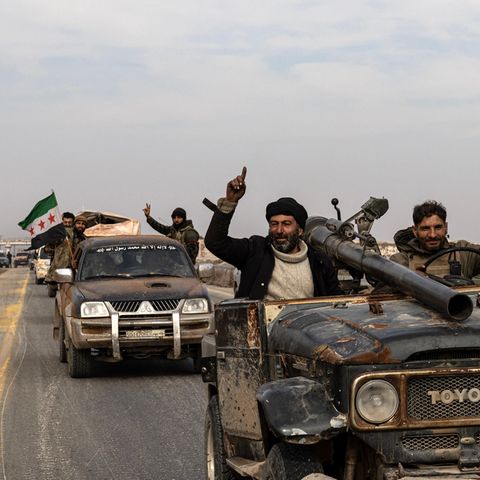 HTS supporters drive down a street and celebrate