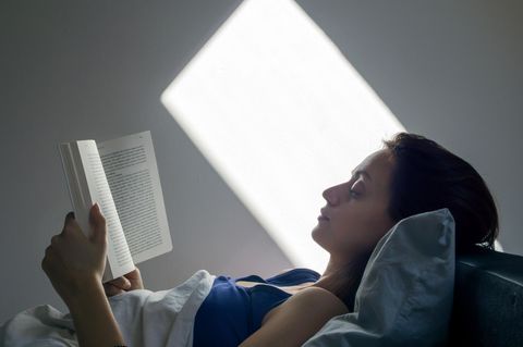Eine Frau liegt im Bett und liest ein Buch.