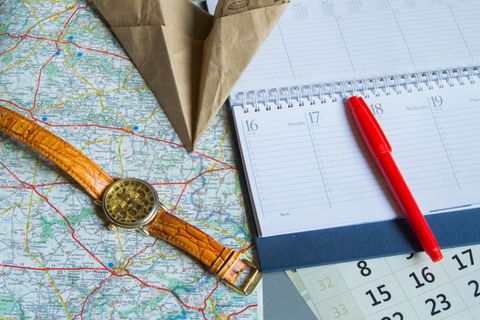 Brückentage: Eine Armbanduhr, ein Kalender und ein Papierflieger auf einer Landkarte