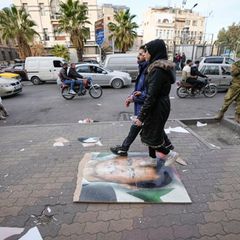 Fußgänger gehen in Damaskus über ein Bild des ehemaligen syrischen Präsidenten Assad 