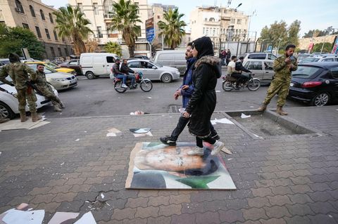 Fußgänger gehen in Damaskus über ein Bild des ehemaligen syrischen Präsidenten Assad 