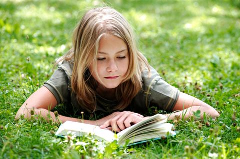 Kinderbücher: Ein Junge liegt auf einer Wiese und liest in einem Buch