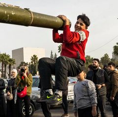 Ein Jugendlicher hält sich in Damaskus aus lauter Freude über den Umsturz in Syrien an einem Panzerrohr fest