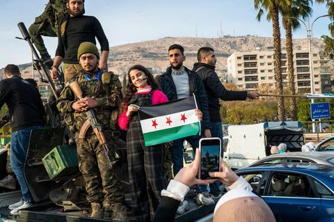 Menschen in Syrien jubeln mit HTS-Kämpfern