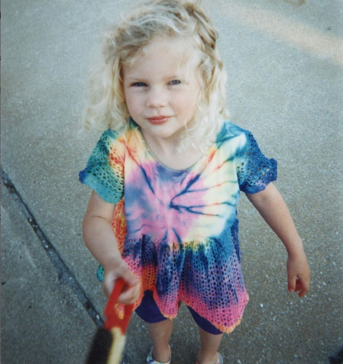 Taylor Swift als kleines Kind mit bloinden Locken in einem Batik-T-Shirt