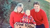 Taylor Swift als Baby mit ihren Eltern. Mutter Andrea und Vater Scott tragen beide rote Pullover