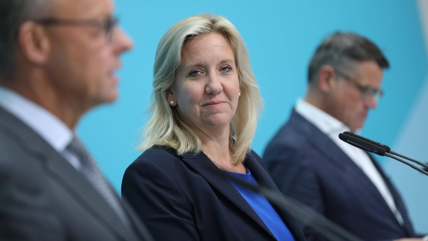 Ines Claus guckt in die Kamera, im Profil erkennt man Friedrich Merz