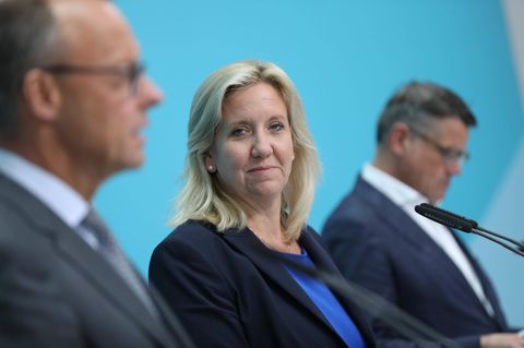 Ines Claus guckt in die Kamera, im Profil erkennt man Friedrich Merz