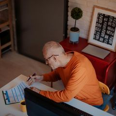 Rentenpunkte kaufen: Älterer Mann sitzt am Schreibtisch und rechnet