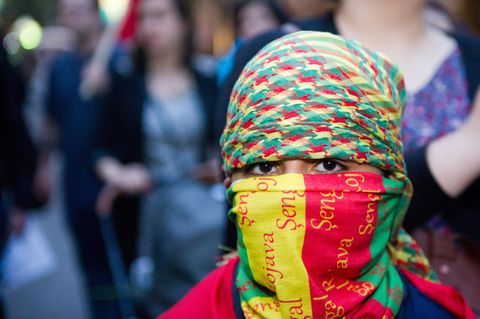 Ein kleiner Junge in den kurdischen Nationalfarben vermummt