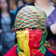 Ein kleiner Junge in den kurdischen Nationalfarben vermummt