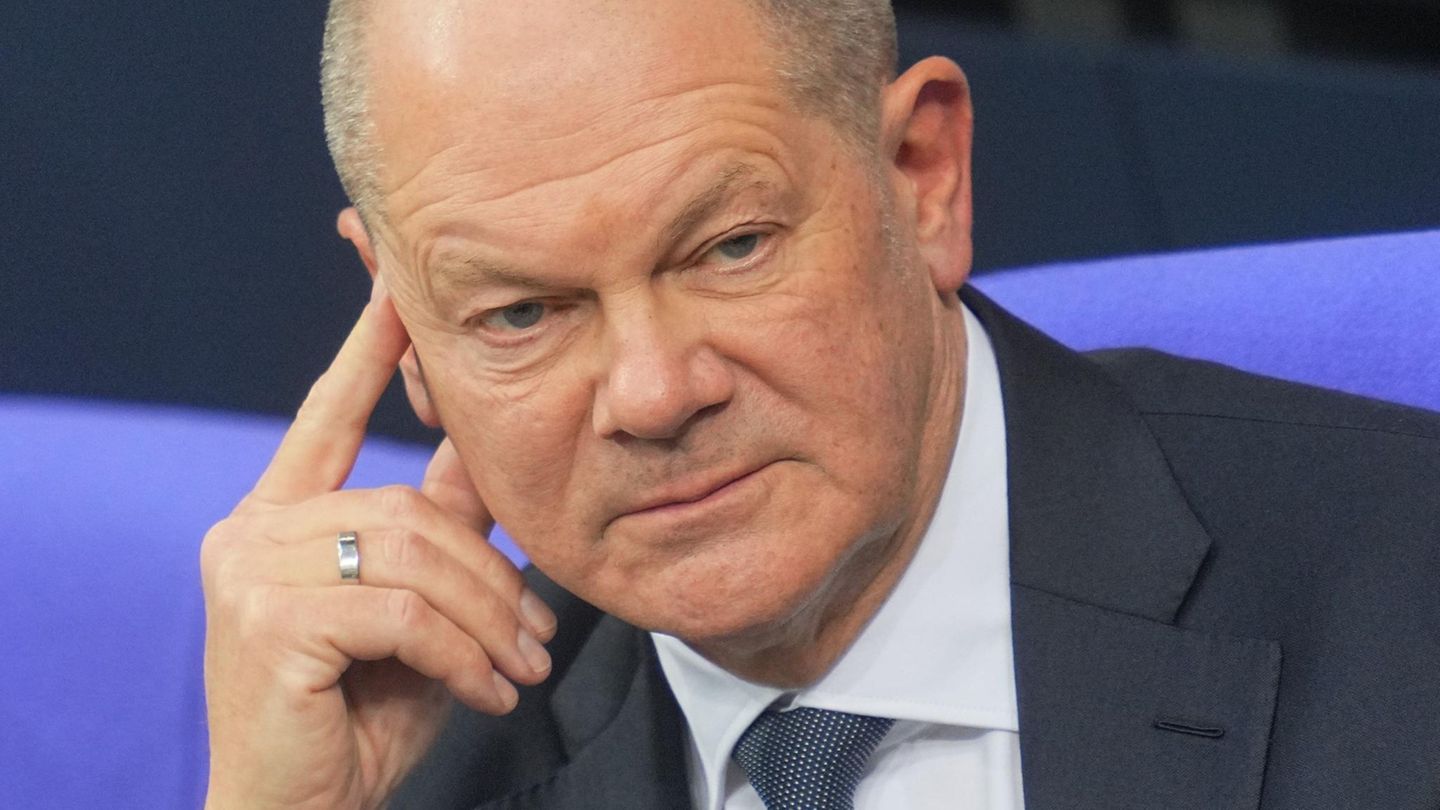 Kanzler Olaf Scholz sitzt am Tag der Vertrauensfrage im Bundestag, hält Zeigefinger an die Schläfe.