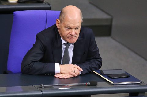 Kanzler Olaf Scholz sitzt am Tag der Vertrauensfrage im Bundestag, hält Zeigefinger an die Schläfe.