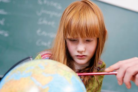 Bob Blume: Ein Mädchen schaut auf einen Globus, auf dem ihr ein Lehrer etwas zeigt