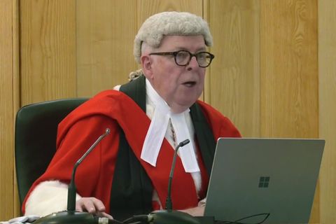In Großbritannien sitzt Richter John Cavanagh in roter Robe und weißer Perücke im Gericht