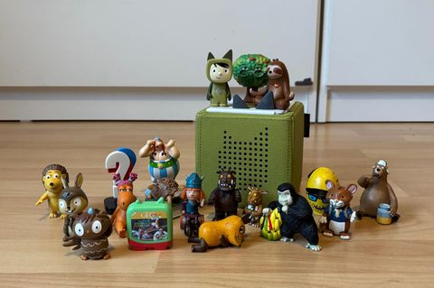 Tonie Hörfiguren: Etwa 20 Tonies stehen neben einer grünen Toniebox