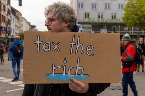 Steuern: Mann mit Plakat "Tax the rich"