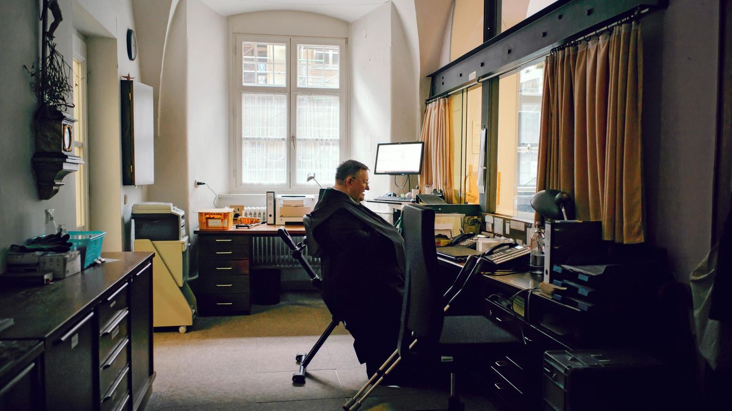 Pater Godehard sitzt im inneren der Pforte im Büro
