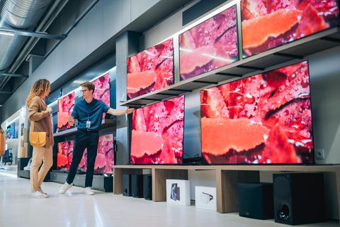 Stiftung Warentest Fernseher: Ein Verkäufer zeigt einer Frau verschiedene TV-Modelle