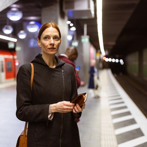 Eine Pendlerin steht am U-Bahnhof in Frankfurt, wartet auf die Abfahrt des Zuges und denkt über ihr Gehalt nach?