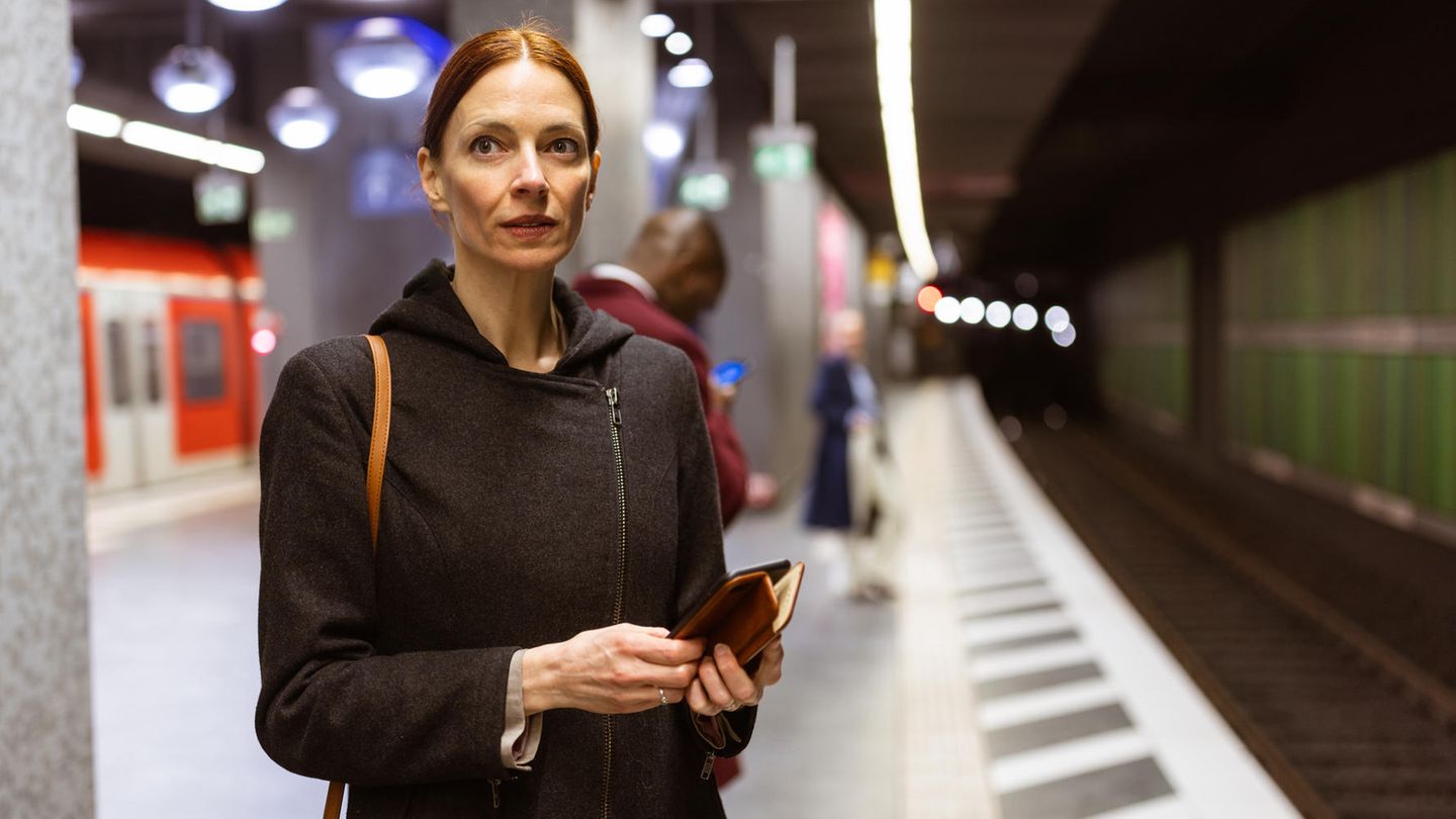 Pendlerin steht am U-Bahnhof in Frankfurt, wartet auf den Zug zur Arbeit und ist in Gedanken: übers Gehalt? Pendlerin steht am U-Bahnhof in Frankfurt, wartet auf den Zug zur Arbeit und ist in Gedanken: übers Gehalt?