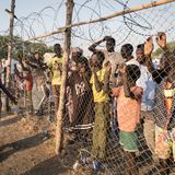 Die Frau ist gerade mit dem Schiff angekommen ist. Hinter dem Zaun warten Menschen, die bereits im Camp leben, auf Verwandte