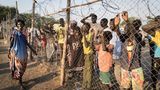 Die Frau ist gerade mit dem Schiff angekommen ist. Hinter dem Zaun warten Menschen, die bereits im Camp leben, auf Verwandte