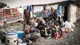 Auch diese Familie ist gerade mit dem Schiff aus Renk angekommen ist. Sie musste sich selbst irgendwie eine Unterkunft im Camp suchen. Die Baracke im Hintergrund ist schon besetzt. Nur ein Teil der Familie kann dort für eine Nacht unterkommen, der Rest muss unter freiem Himmel schlafen