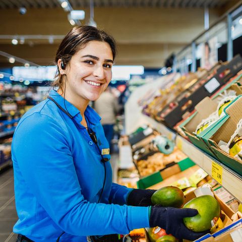 Verkäuferin bei Aldi sortiert Mangos in der Gemüseabteilung