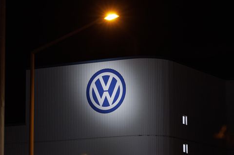 Das Logo von Volkswagen am Werk Osnabrück wird bei Dunkelheit von einem Scheinwerfer angestrahlt