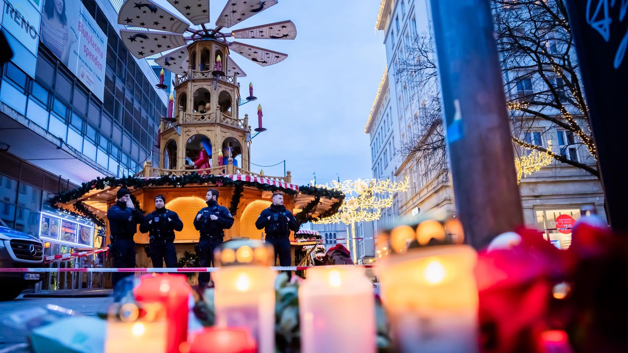 Kerzen vor Polizisten auf dem Weihnachtsmarkt in Magdeburg