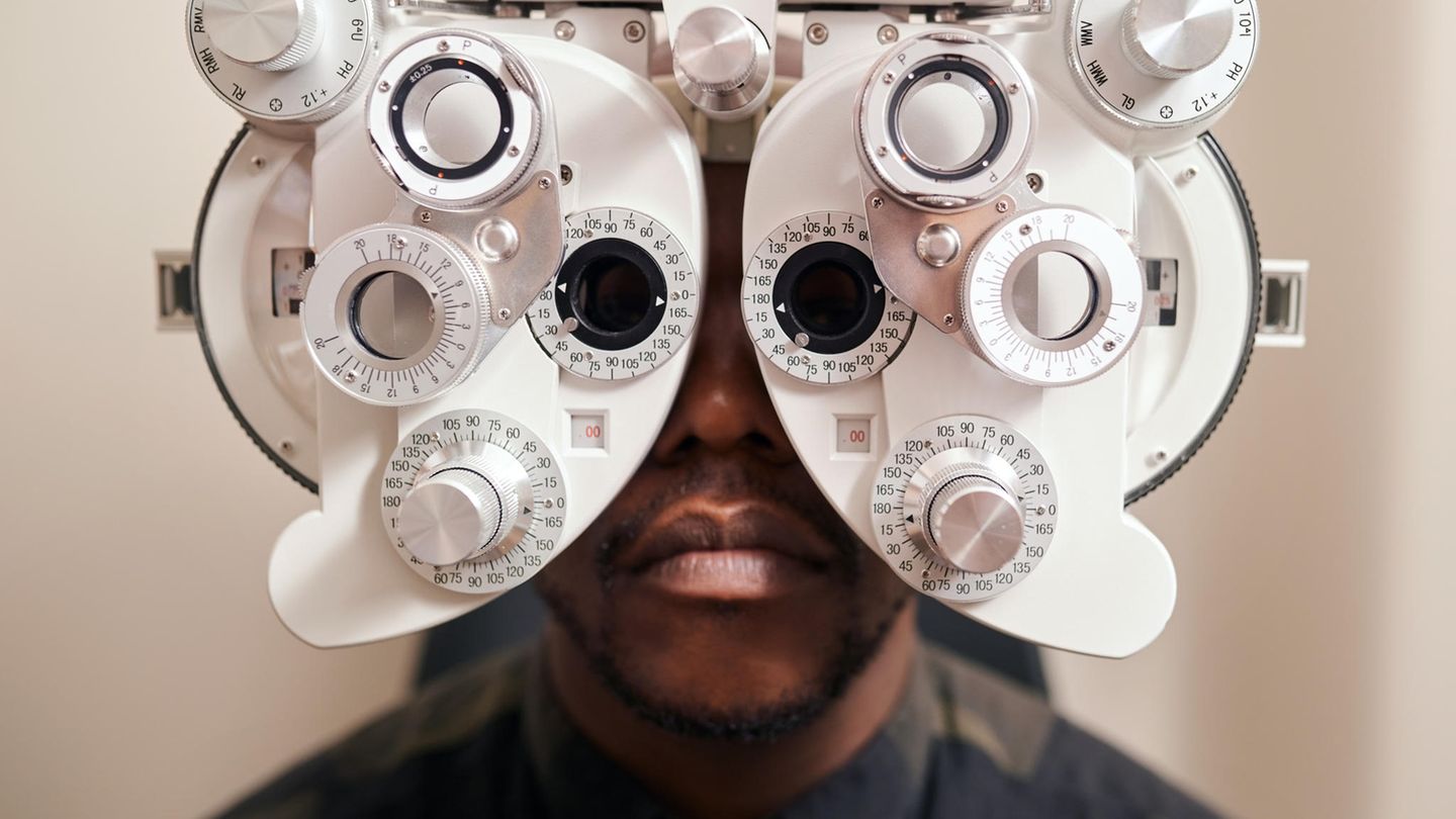 Ein Mann der vor den Augen ein großes Gerät zum Augen testen hat