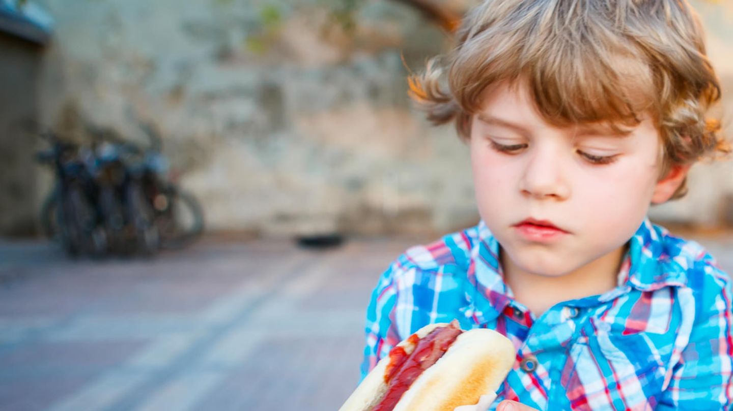 Familienessen: Ein Junge schaut skeptisch auf seinen Hotdog