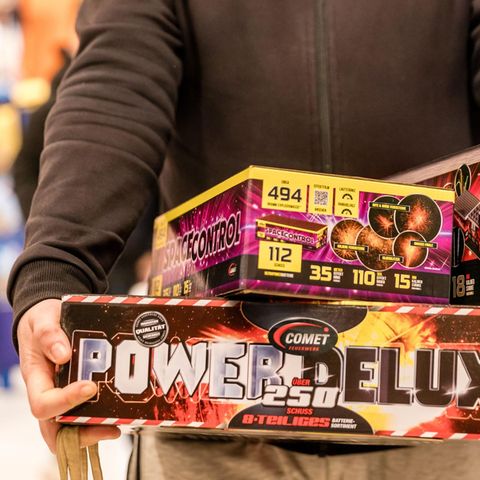 Ein Mann trägt Kartons mit Silvester-Feuerwerk aus einem Supermarkt