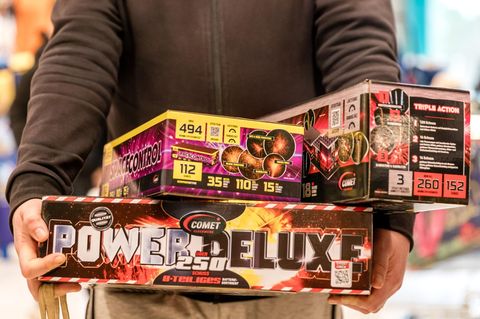 Ein Mann trägt Kartons mit Silvester-Feuerwerk aus einem Supermarkt