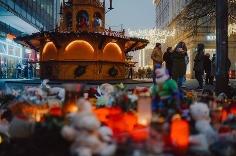 Grabkerzen und Kuscheltiere stehen vor einem Stand auf dem Weihnachtsmarkt in Magdeburg