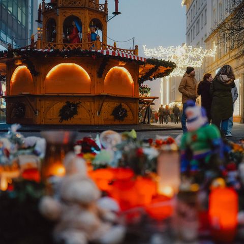 Grabkerzen und Kuscheltiere stehen vor einem Stand auf dem Weihnachtsmarkt in Magdeburg