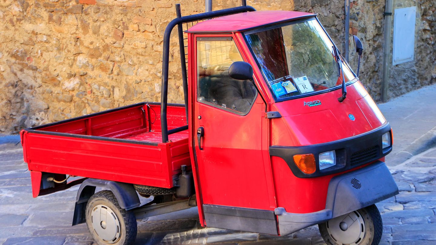 Eine rote Piaggio Ape steht in Italien in einer Gasse