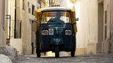 Eine Piaggio Ape fährt durch enge Gassen einer italienischen Stadt
