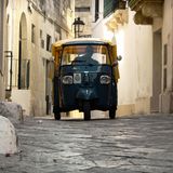 Eine Piaggio Ape fährt durch enge Gassen einer italienischen Stadt