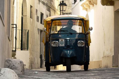 Eine Piaggio Ape fährt durch enge Gassen einer italienischen Stadt