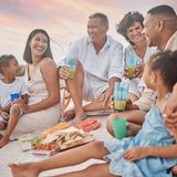 In Südafrika sitzen Erwachsene und Kinder bei einem Silvester-Picknick am Strand