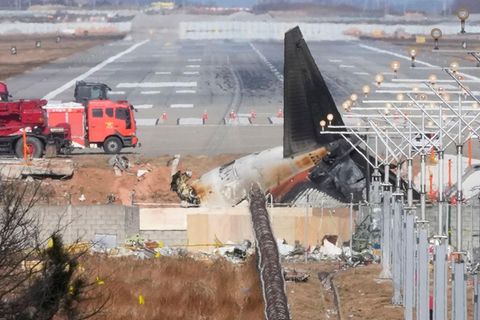Hinter einer Mauer liegt ein Flugzeugwrack auf dem Flughafen in Muan, Südkorea